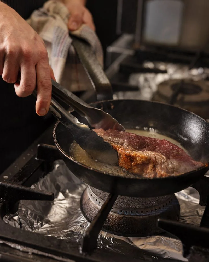 A juicy steak sizzles in a pan, showing the expert cooking happening in the kitchen of a popular Temple Bar dining spot.
